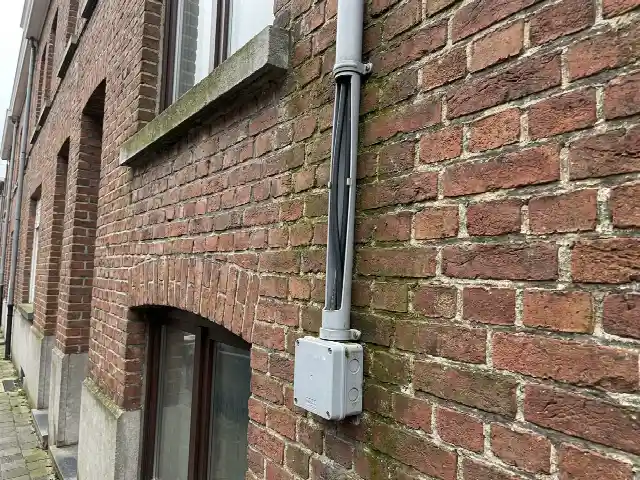 Gaine de câbles solaires descendant le long d'une façade en briques