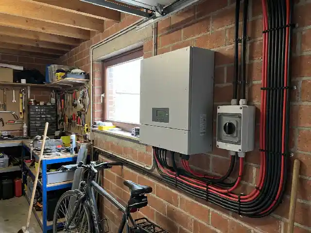 Onduleur fixé au mur d'un garage avec ses câbles